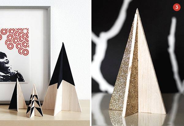 Three beige and black paper Christmas trees on a table and one beige and white paper folded Christmas tree