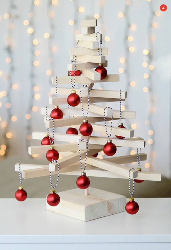 Christmas tree decoration made from white wood slats with red ball ornaments.