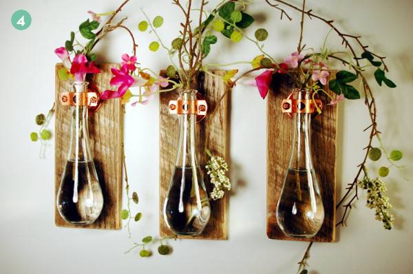 Three glass vases attached to wooden boards hanging on a wall.