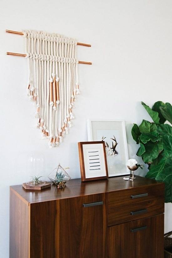 A wall hanging is made of many white strands of fiber with brown accents.