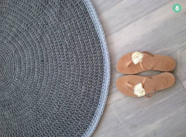 A pair of sandals sits by a round blue rug.