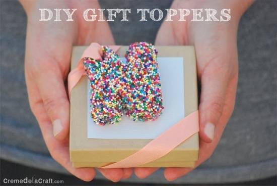 A person holding a small gift box that has a letter covered in colorful sprinkles.