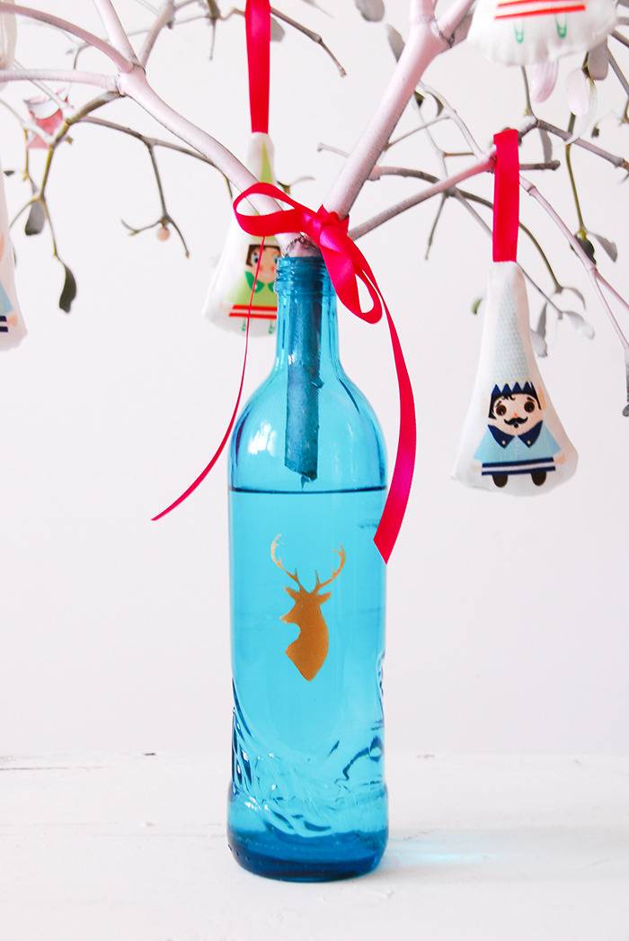 A blue bottle with a deer's head graphic on it has branches sticking out of it.