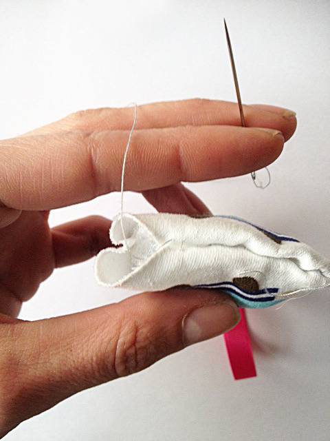 A finger puppet is being handsewn.