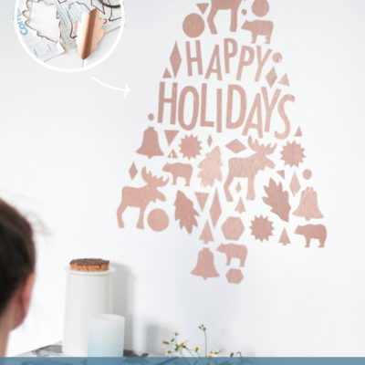 A wall art made on a wall in the Christmas tree shape with Happy Holidays written in it.