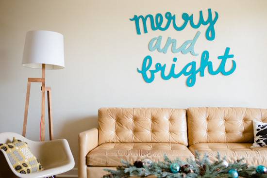 Large paper cutouts read "merry and bright" in cursive on a living room wall.