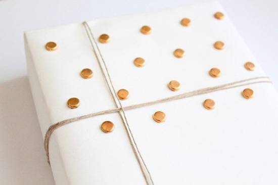 White paper with copper circles covers a gift wrapped with twine as a bow