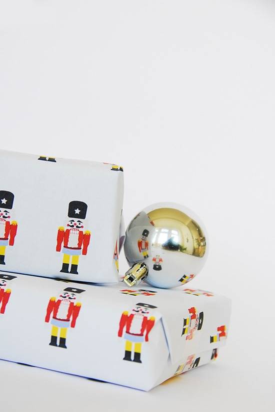 Gifts with nutcracker wrapping paper and a silver Christmas ornament.