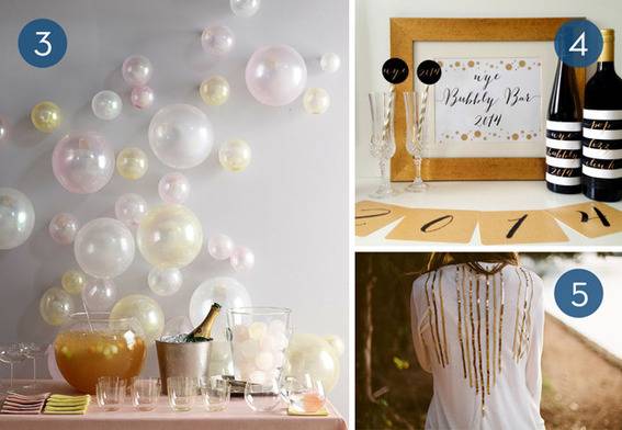 A table with a punchbowl, champagne in a bucket, glasses and a glass bucket of round ice cubes against a wall full of white balloons, Two bottles, two champagne flutes and a year sign 2014, the back of a white shirt with gold chains down the back.