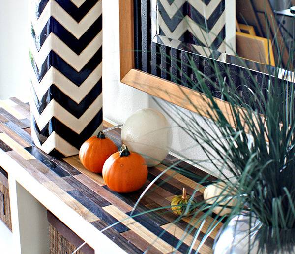 White and black pattern shelf with potted plant and toy pumpkins.