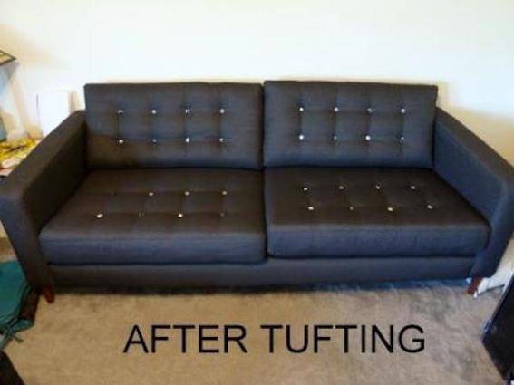 Black couch with tufted cushions in a living room.