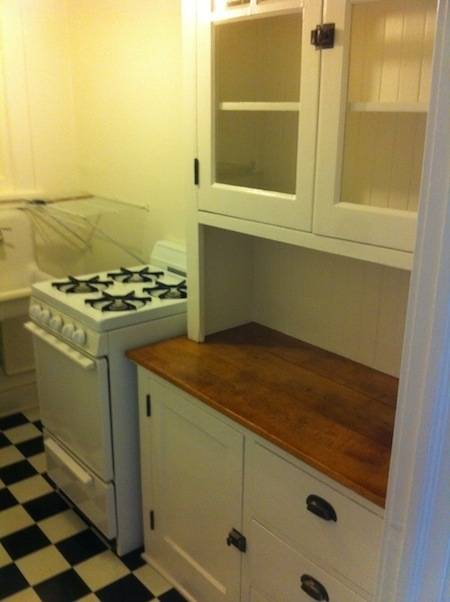 Small kitchen with checkered floors, old counters and cabinets.