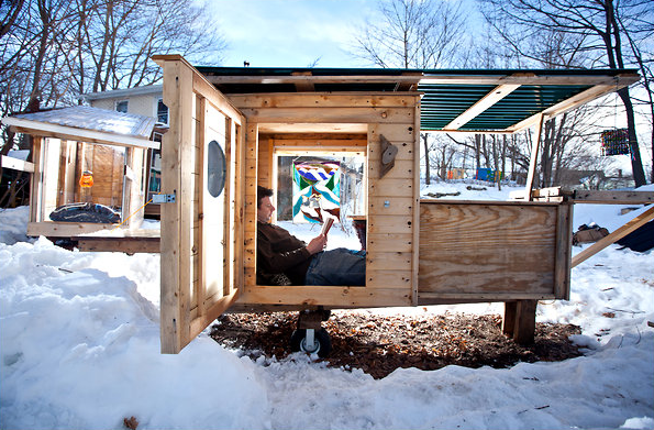 Man sitting on a bed and reading a book in a tiny home.