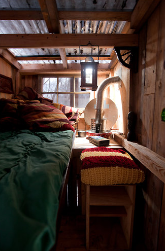 A small bedroom with a desk and stool chair.