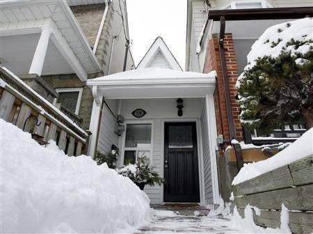 A black door is in front of a white building where it has snowed recently.