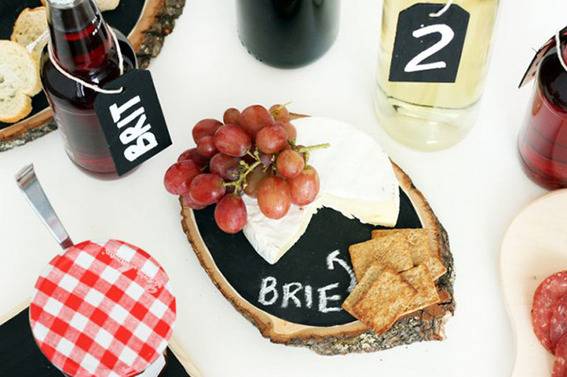 A cheese spread with crackers, jam, and wine.