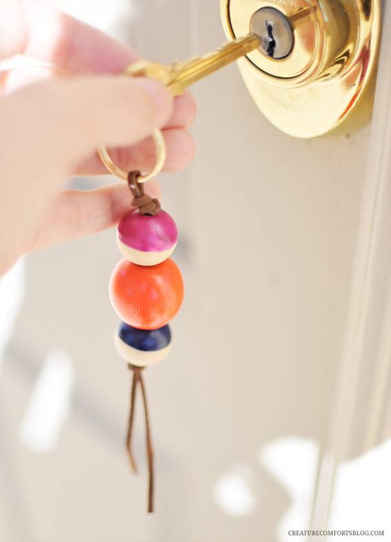 A person is about to insert a key in a door with beads key chain.