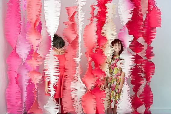 Two kids are standing behind the decorative papers.