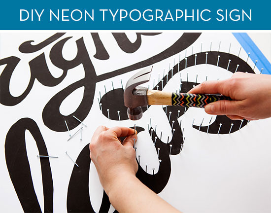 A person uses a hammer to tap small nails into a sign going around the lettering