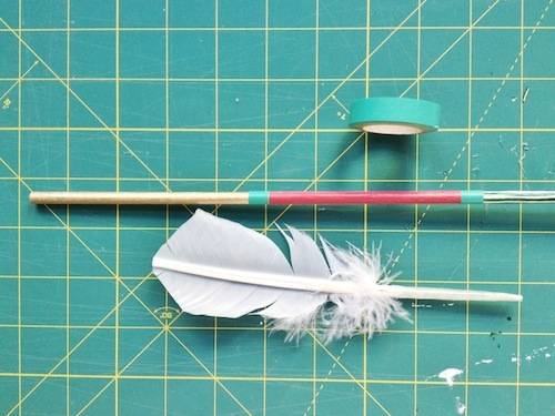 A feather, tape, and a long straw on a measuring table.