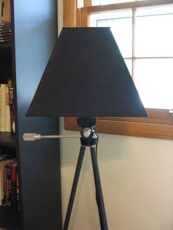 "Black night lamp is on the corner of the room."