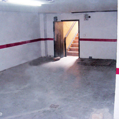 An empty garage with white walls and cement floor.