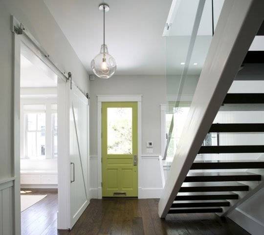 Inside of the house with staircase, wooden floor and green color main door.