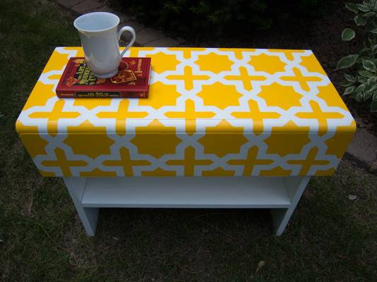 Side table with a yellow and white cross pattern on the top.