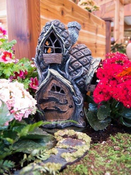 Small garden gnome house decoration between two flower bushes.