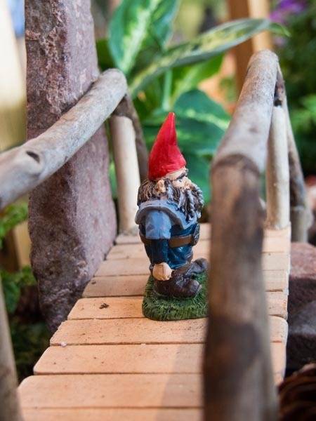 A garden gnome is standing on a wooden pier.