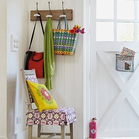 Enteryway of home has a multicolored chair and a coat rack.