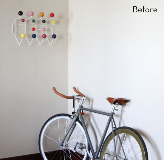 A white wall has hanging decor and a bike in front of it.