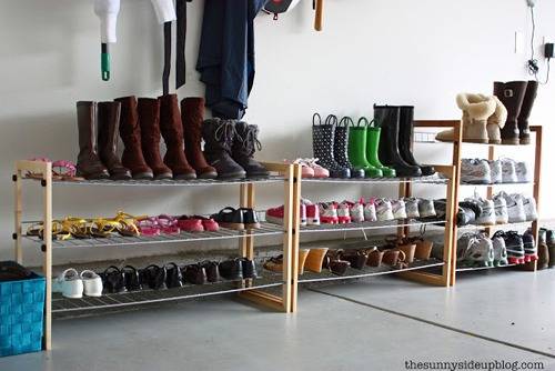 Several shoe racks in the garage with lots of shoes on top of them.