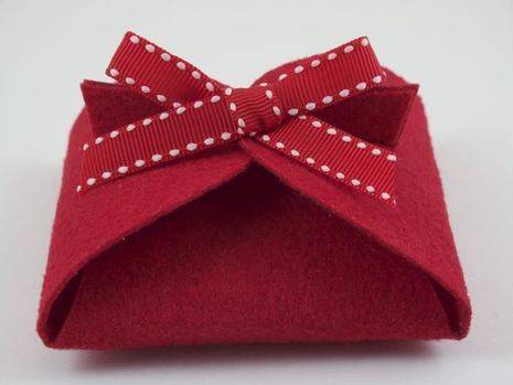 Red color fabric gift box with red spotted ribbon on top.