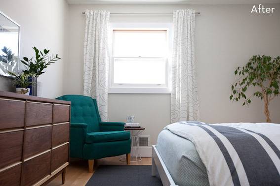 A green chair is sitting near a window in a room with a brown dresser.