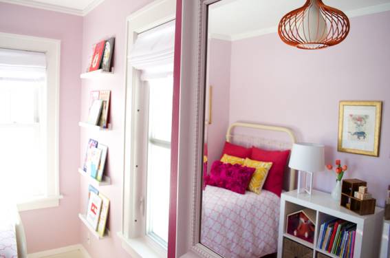 A girl's rom with pink walls and bed blanket.