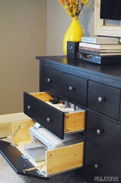 A black shelf has open drawers and books on top.
