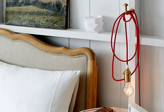 An Edison bulb is hanging next to the bed over the nightstand.