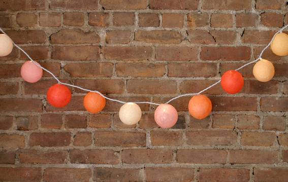 "Colourful light balls hanging on the brick wall."