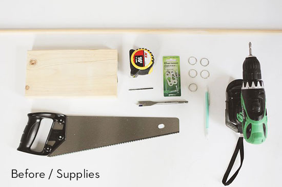 Supplies for a DIY project which include a drill, a saw, metal rings, a ruler, a panel of wood, and a wood shaver.