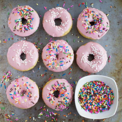 Donuts with pink icing and colorful sprinkles.