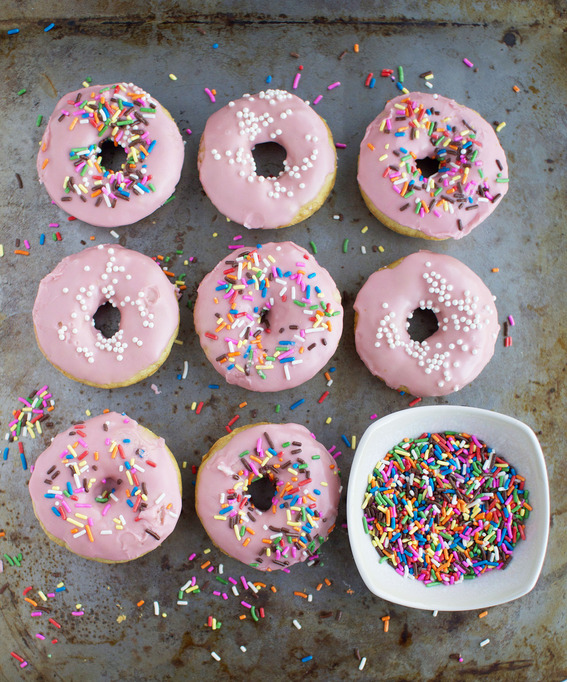 Donuts with pink icing and colorful sprinkles.