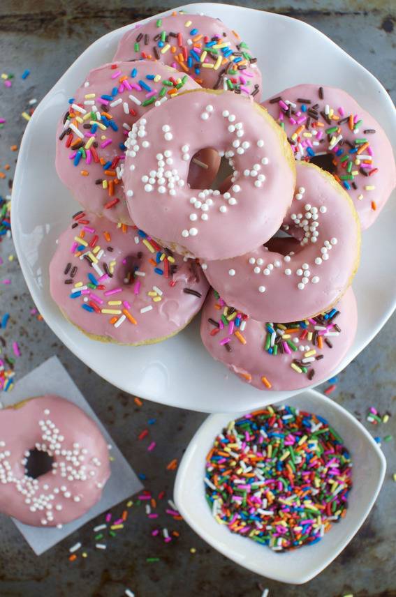 Donuts with pink frosting and colorful sprinkles on top.