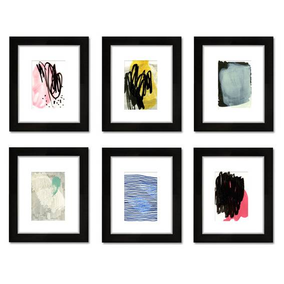 A collection of different abstract paintings in black picture frames