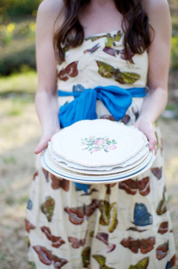 A woman in a butterfly dress holds a cake.