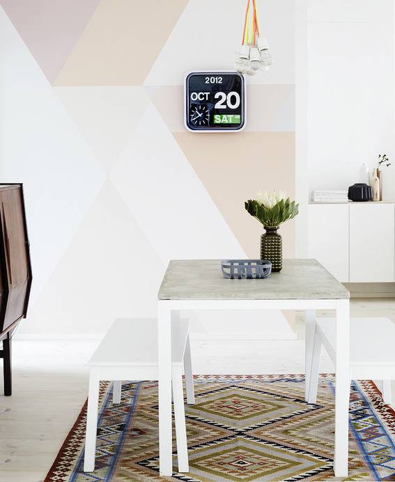 "White table with plant is on the designer carpet and modern calendar hanging."