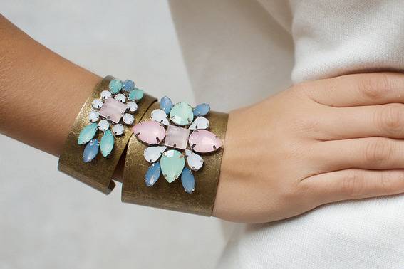 Two brown bracelets with jewels on them are on a person’s wrist.