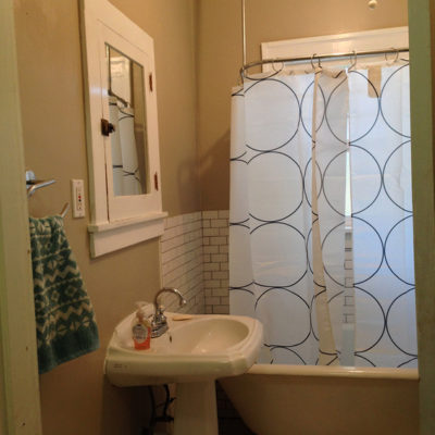 Bathroom with tub, commode toilet, washbasin and mirror.