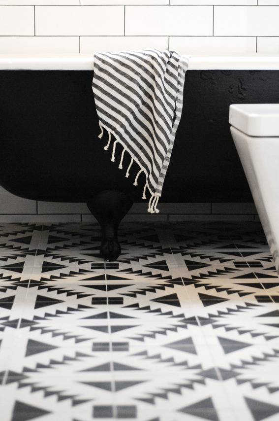 A black bathtub sits on a patterned floor.