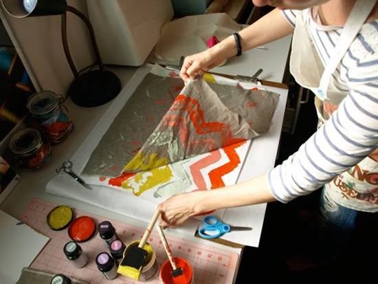 A person works on a craft with orange and yellow paint.